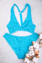 Photo of Elegant light blue women's underwear and cotton flowers on grey background, flat lay
