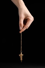 Photo of Psychotherapist with pendulum on black background, closeup. Hypnotherapy session