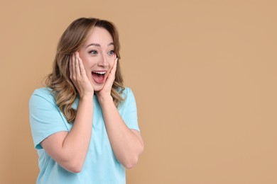 Portrait of happy surprised woman on beige background. Space for text