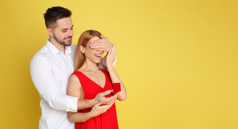Photo of Man with engagement ring making marriage proposal to girlfriend on yellow background