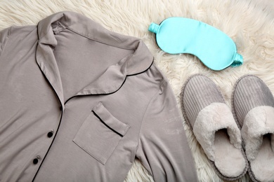 Pair of slippers, pajamas and sleeping eye mask on fuzzy carpet, flat lay. Comfortable home outfit