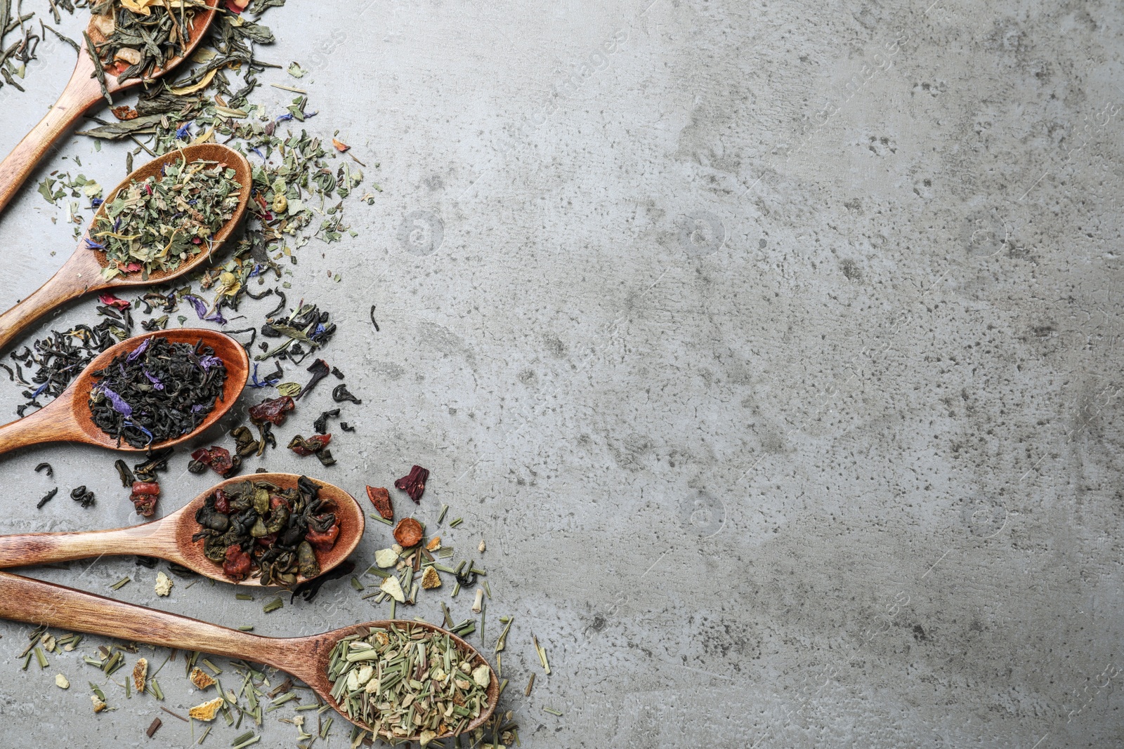 Photo of Flat lay composition with different teas and spoons on light grey stone table. Space for text