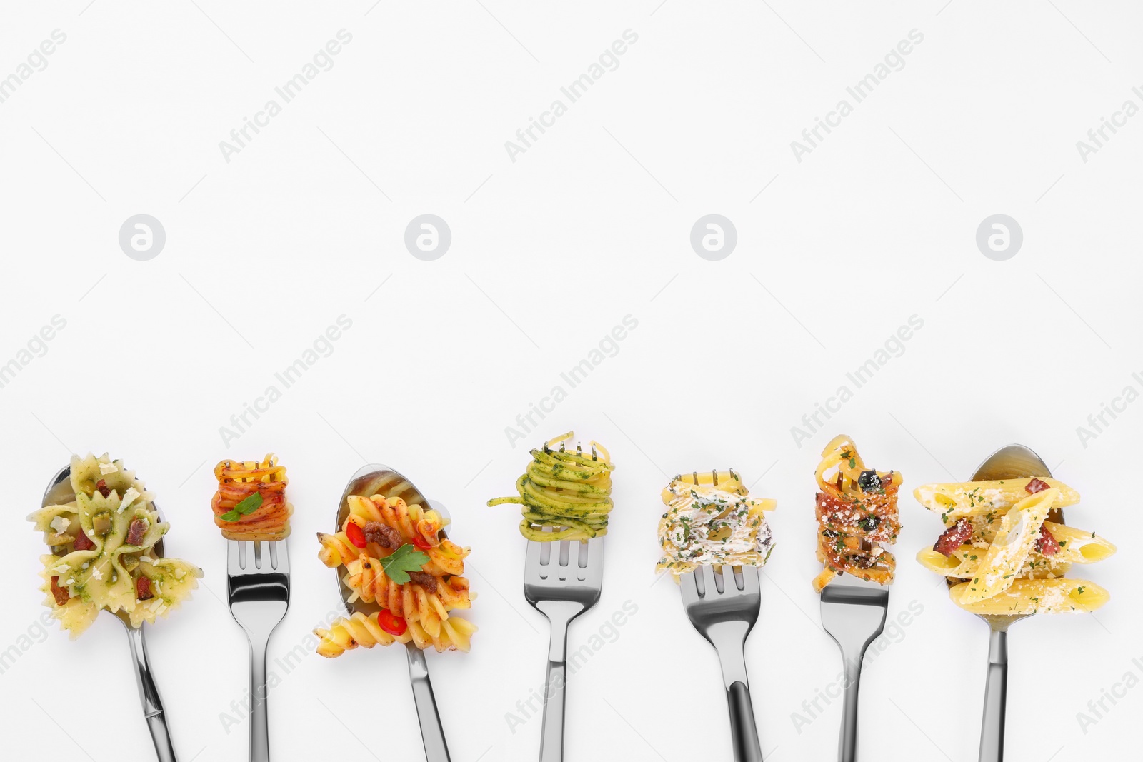 Photo of Forks and spoons with various tasty pasta on white background, flat lay. Space for text