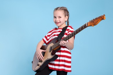 Photo of Cute girl with electric guitar on light blue background