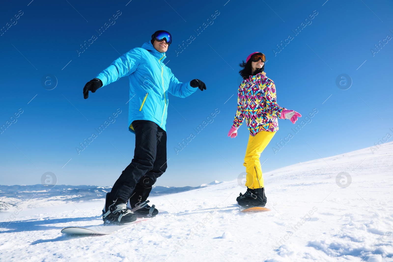 Photo of Couple snowboarding on snowy hill. Winter vacation