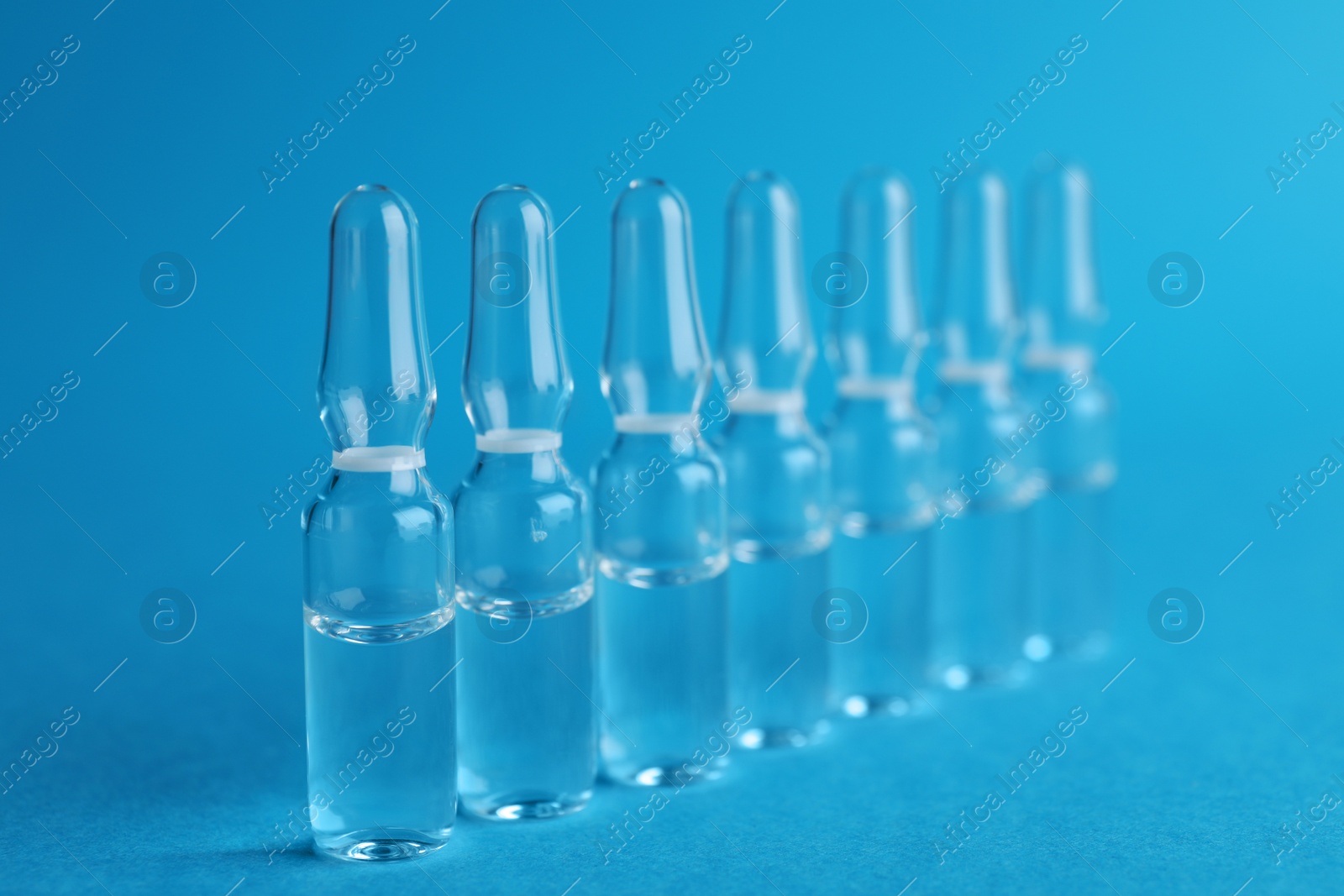 Photo of Many medical ampoules with solution for injection on light blue background