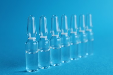 Many medical ampoules with solution for injection on light blue background
