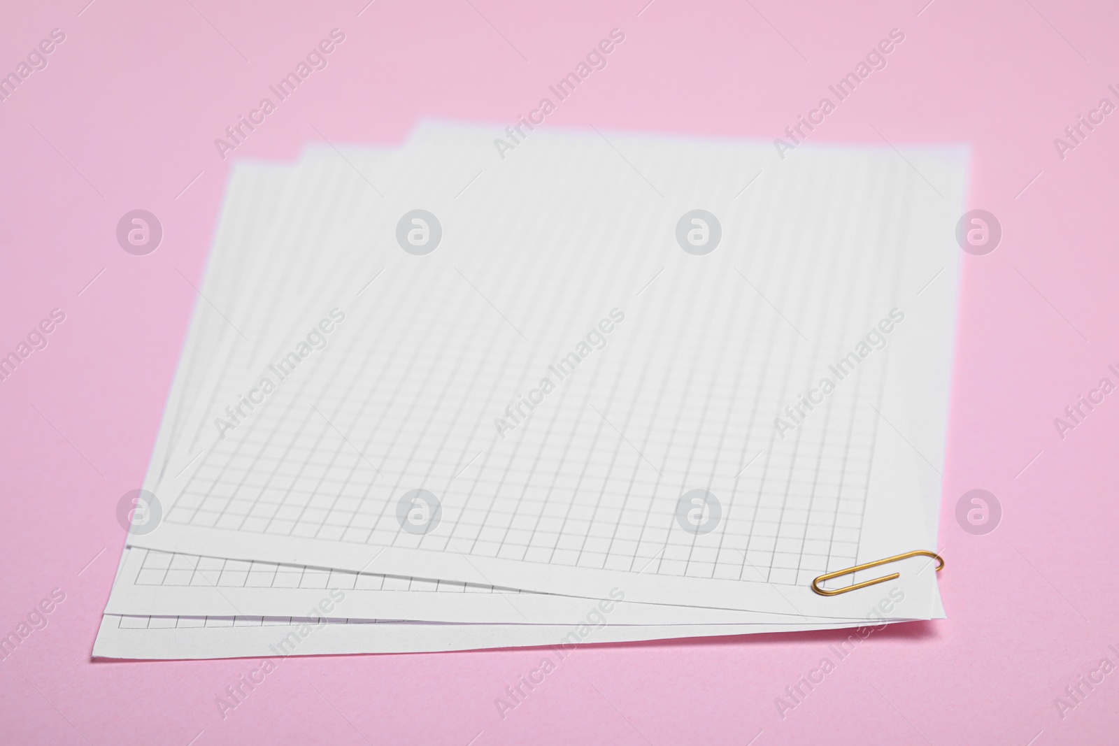 Photo of Sheets of paper with clip on pink background