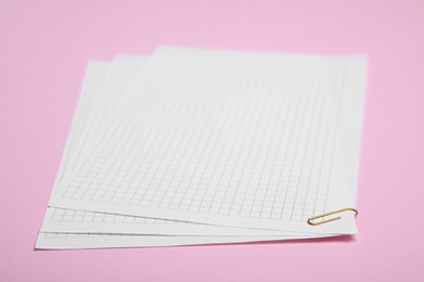 Photo of Sheets of paper with clip on pink background