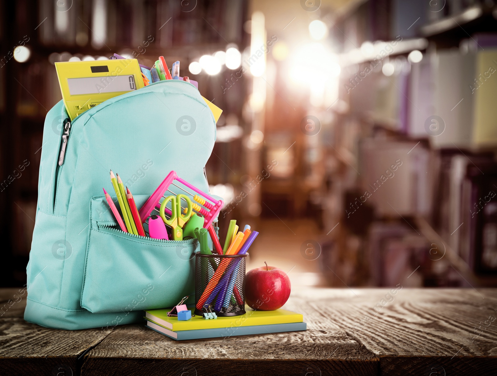 Image of Backpack with school stationery on wooden table in library, space for text