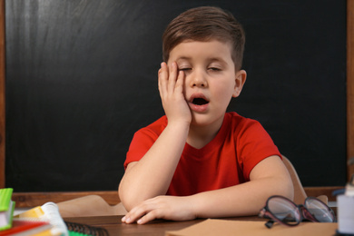 Photo of Cute little child at desk in classroom. First time at school