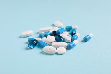 Photo of Many different pills on light blue background, closeup