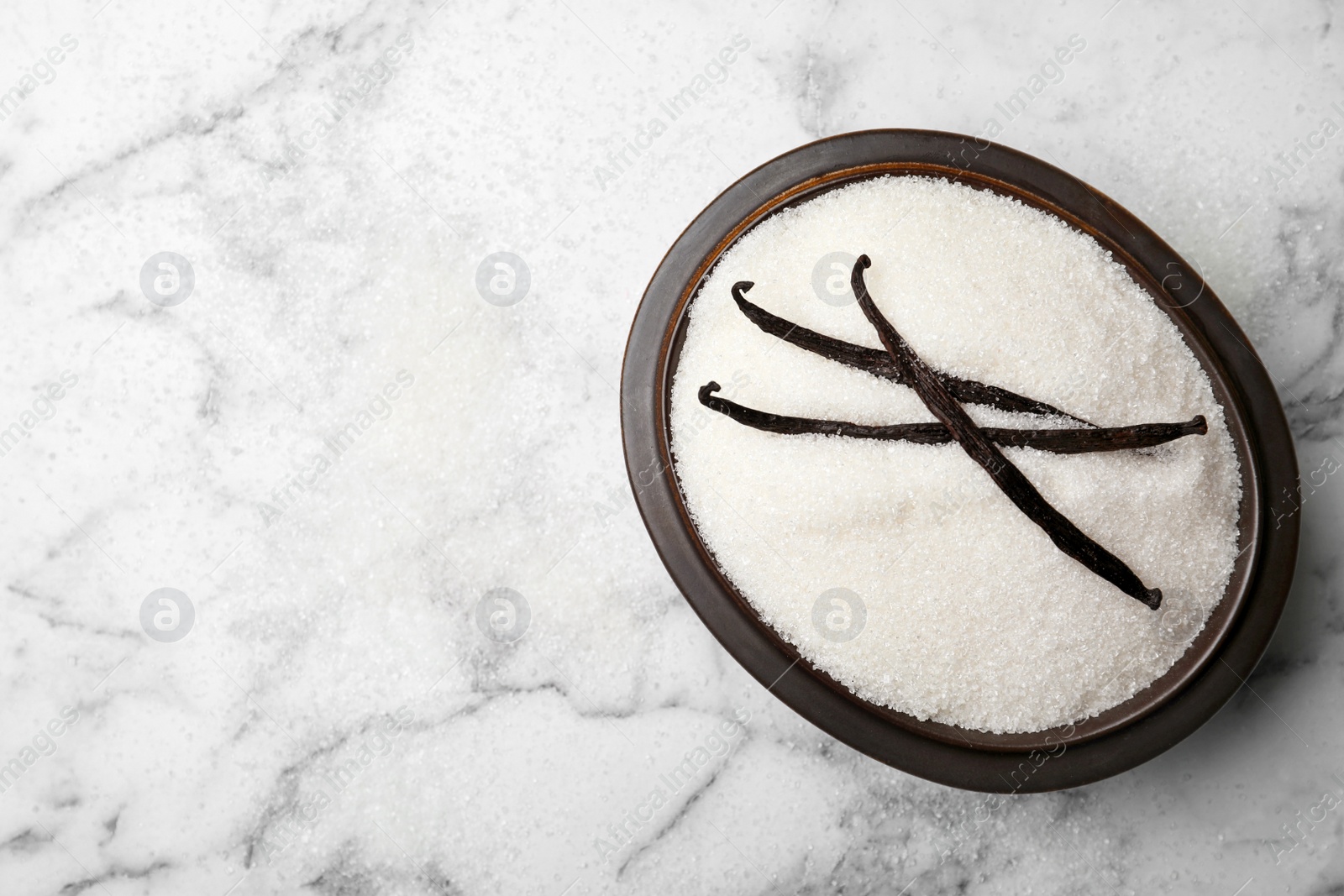 Photo of Bowl of aromatic vanilla sugar and sticks on light background