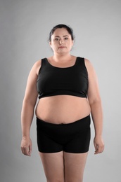 Fat woman on grey background. Weight loss