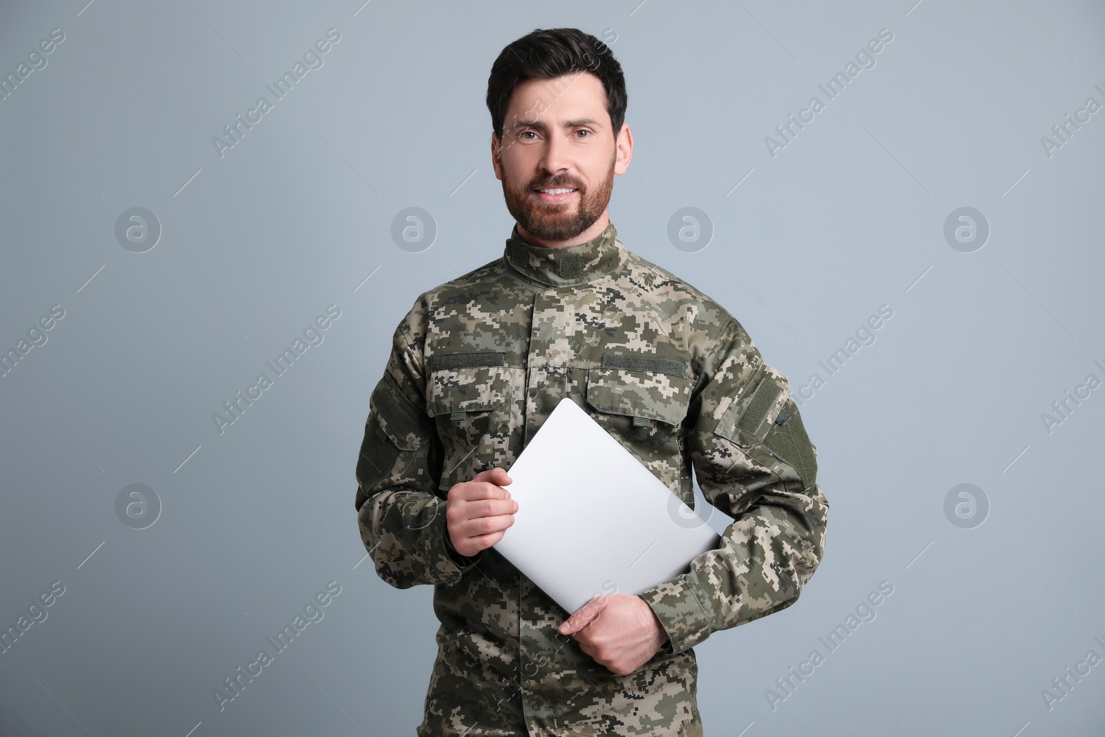 Photo of Soldier with laptop on light grey background. Military service