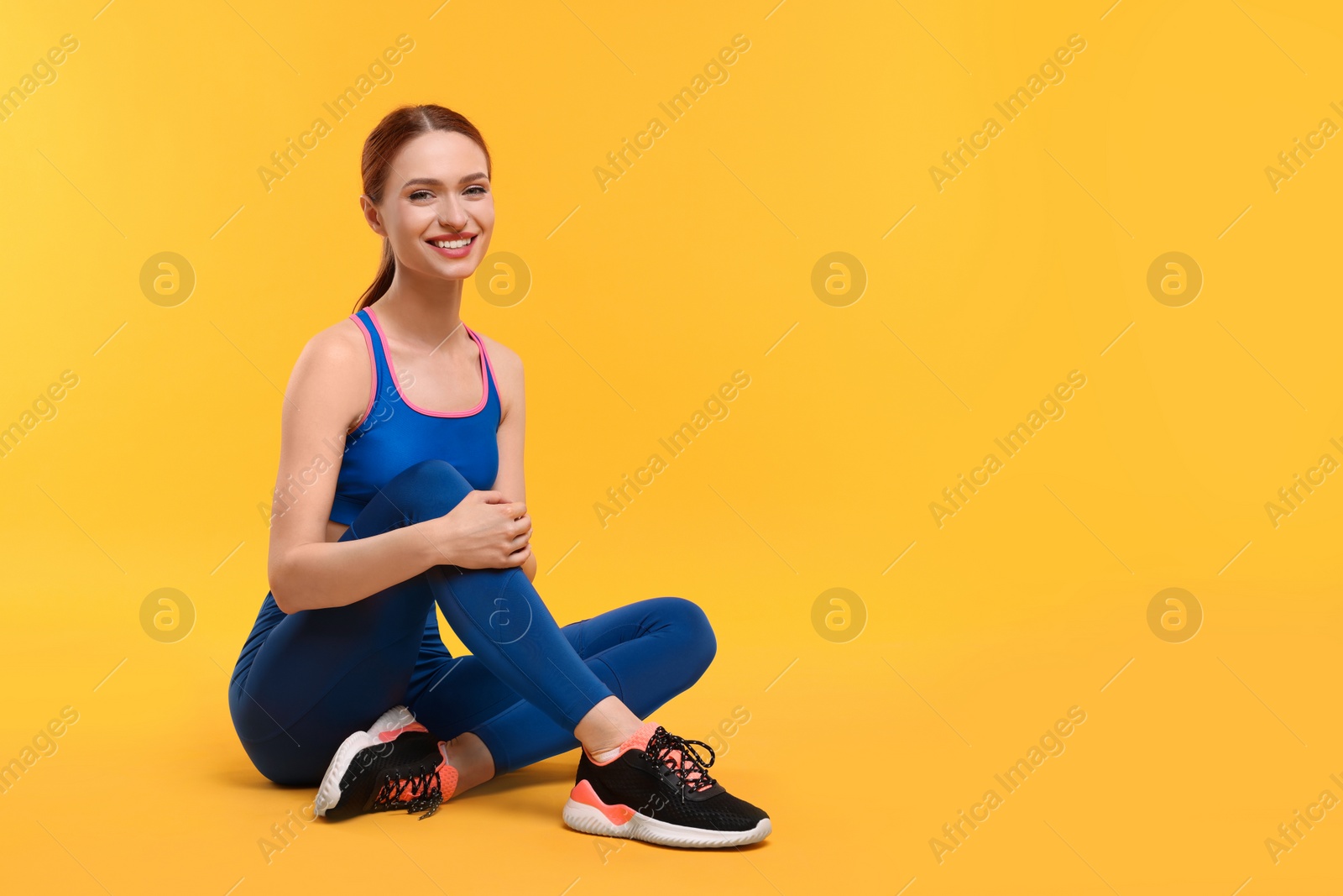 Photo of Young woman wearing sportswear on yellow background, space for text