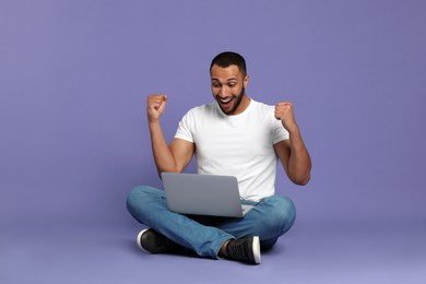 Photo of Happy young man with laptop on lilac background
