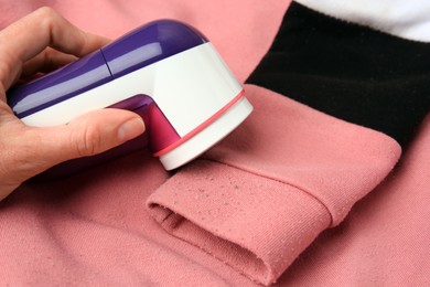 Woman using modern fabric shaver on sweater with lint, closeup