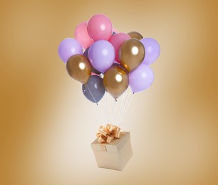 Many balloons tied to gift box on golden background