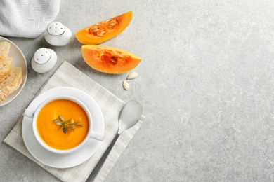 Flat lay composition with pumpkin cream soup in bowl on light background. Space for text