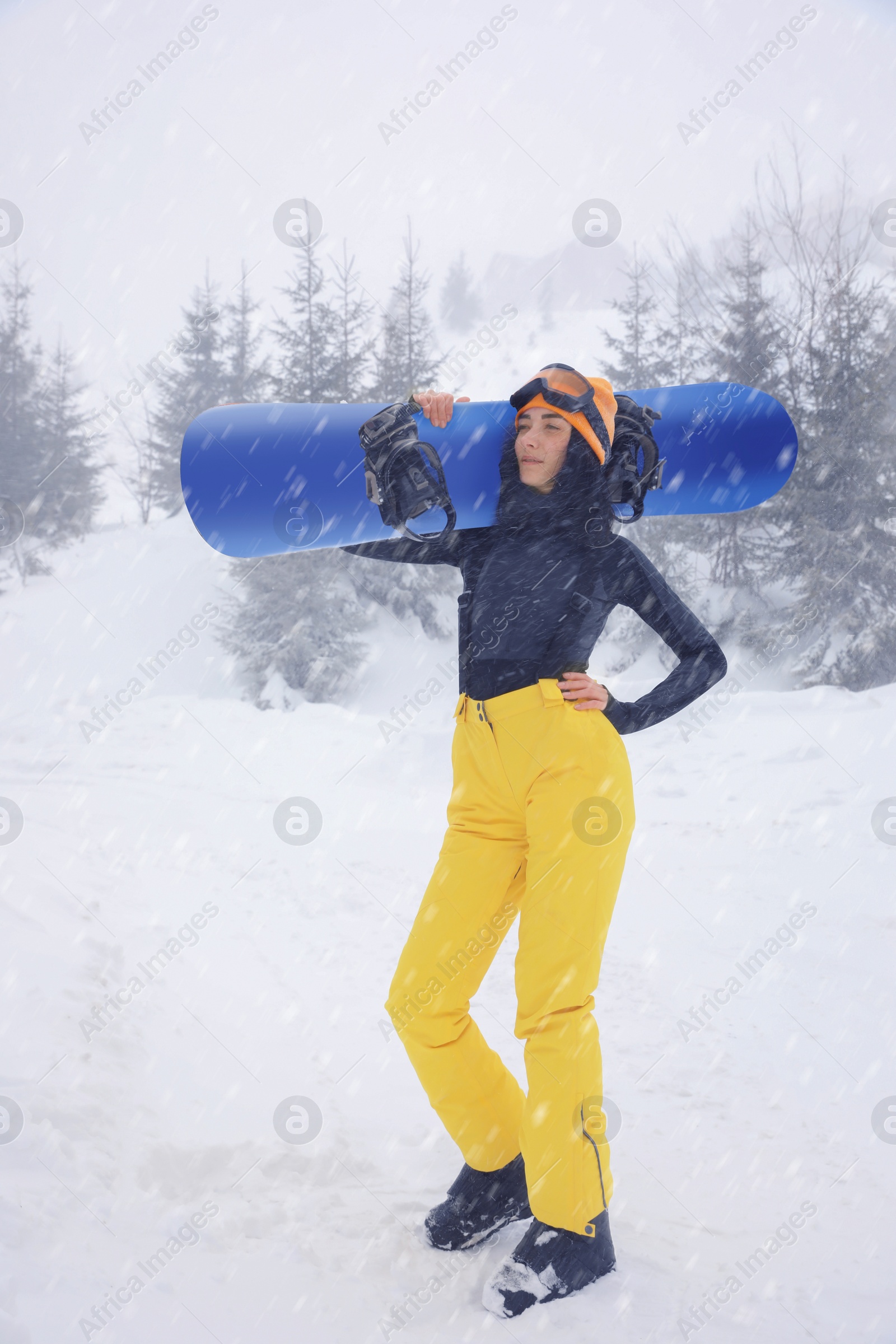 Photo of Young woman with snowboard wearing winter sport clothes outdoors