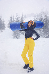 Young woman with snowboard wearing winter sport clothes outdoors