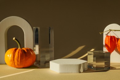 Photo of Stylish presentation for product. Autumn composition with decorative pumpkin and geometric figures on beige background
