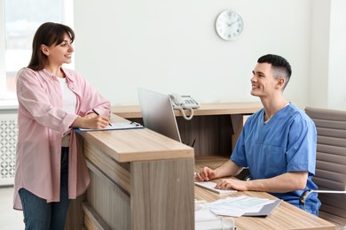 Smiling medical assistant working with patient at hospital reception