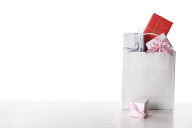Photo of Shopping paper bag with presents on white wooden table