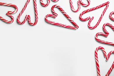 Photo of Hearts made of Christmas candy canes on white background, top view. Space for text