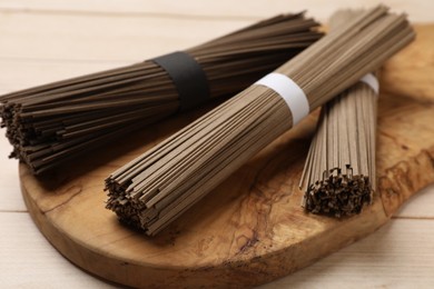 Photo of Uncooked buckwheat noodles (soba) on light wooden table, closeup