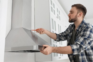 Man repairing modern cooker hood in kitchen