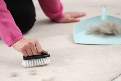 Photo of Woman with brush removing pet hair from carpet at home, closeup