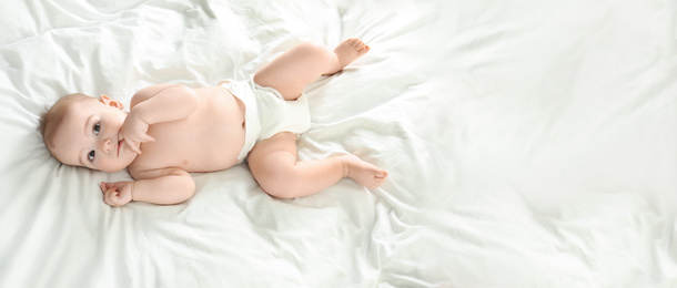 Cute little baby in diaper lying on bed, above view with space for text. Banner design