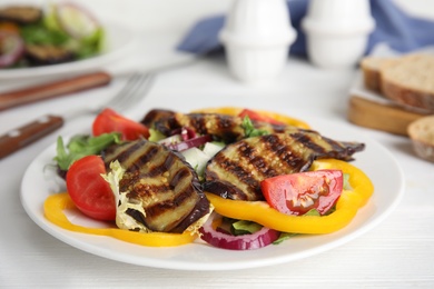 Photo of Delicious salad with roasted eggplant served on white table, closeup