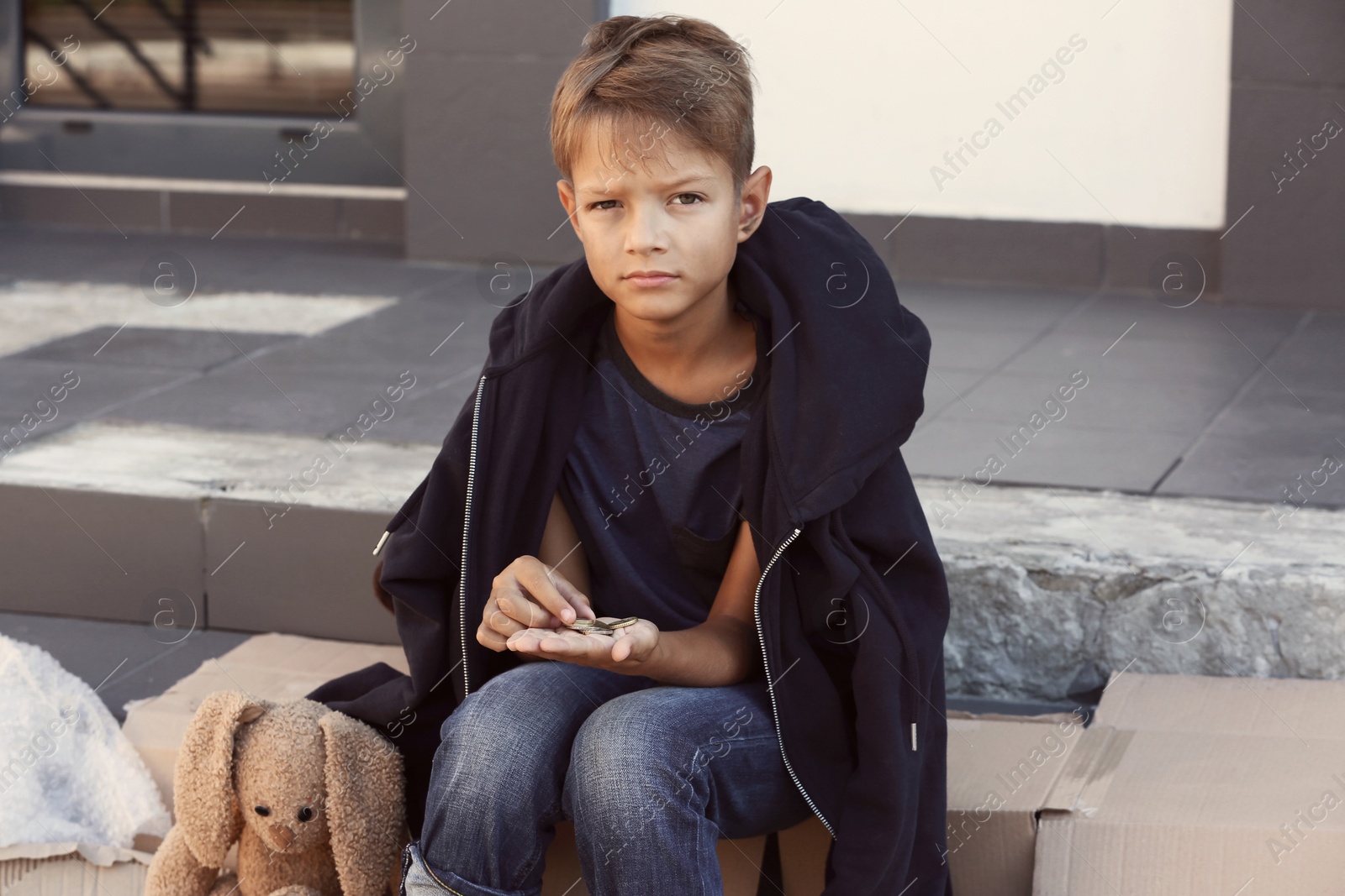 Photo of Poor little boy counting coins on city street
