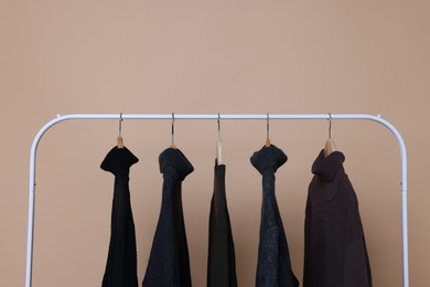 Photo of Rack with different warm sweaters on beige background