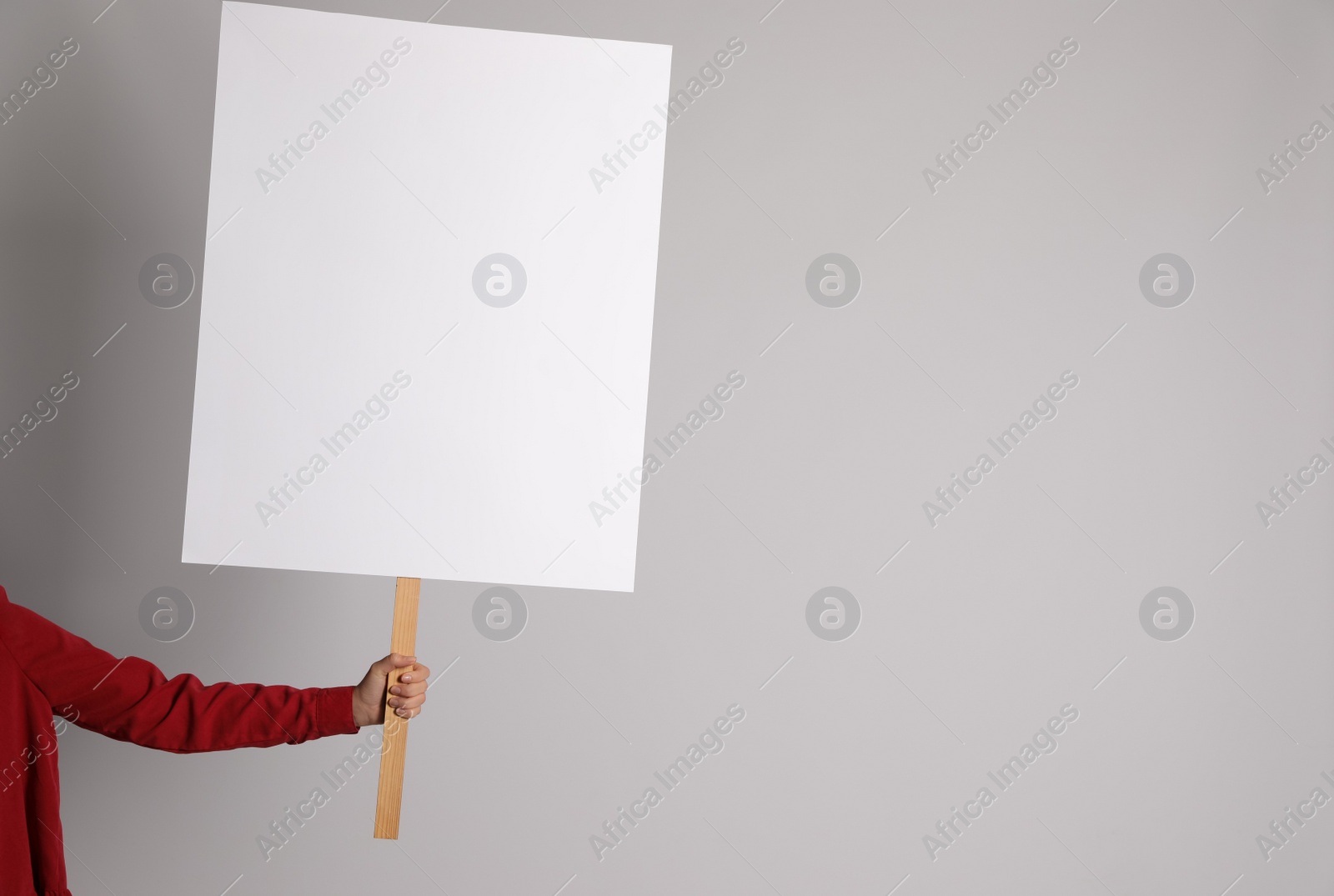 Photo of Woman holding blank sign on light grey background, closeup. Space for design