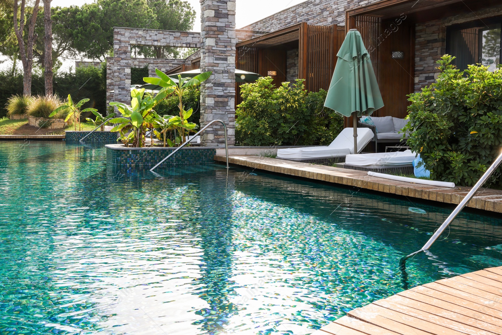 Photo of Swimming pool, exotic plants and sunbeds at luxury resort