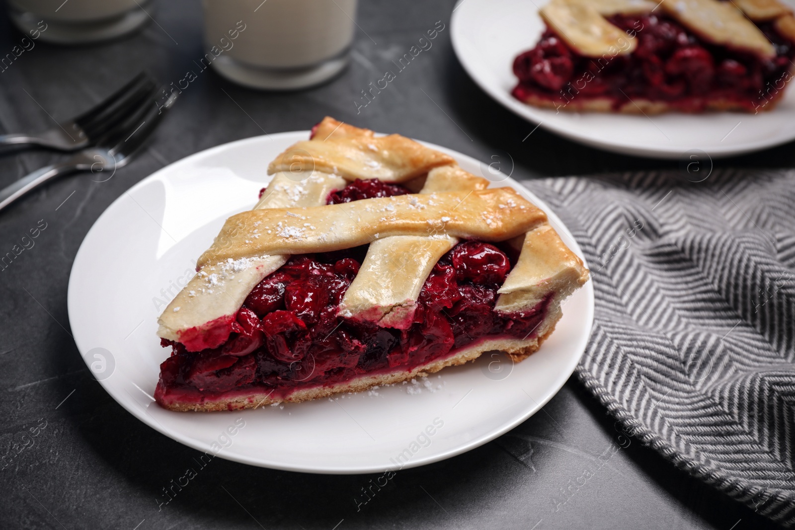 Photo of Slice of delicious fresh cherry pie on grey table, closeup