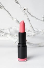 Beautiful pink lipstick and decorative branch on white background