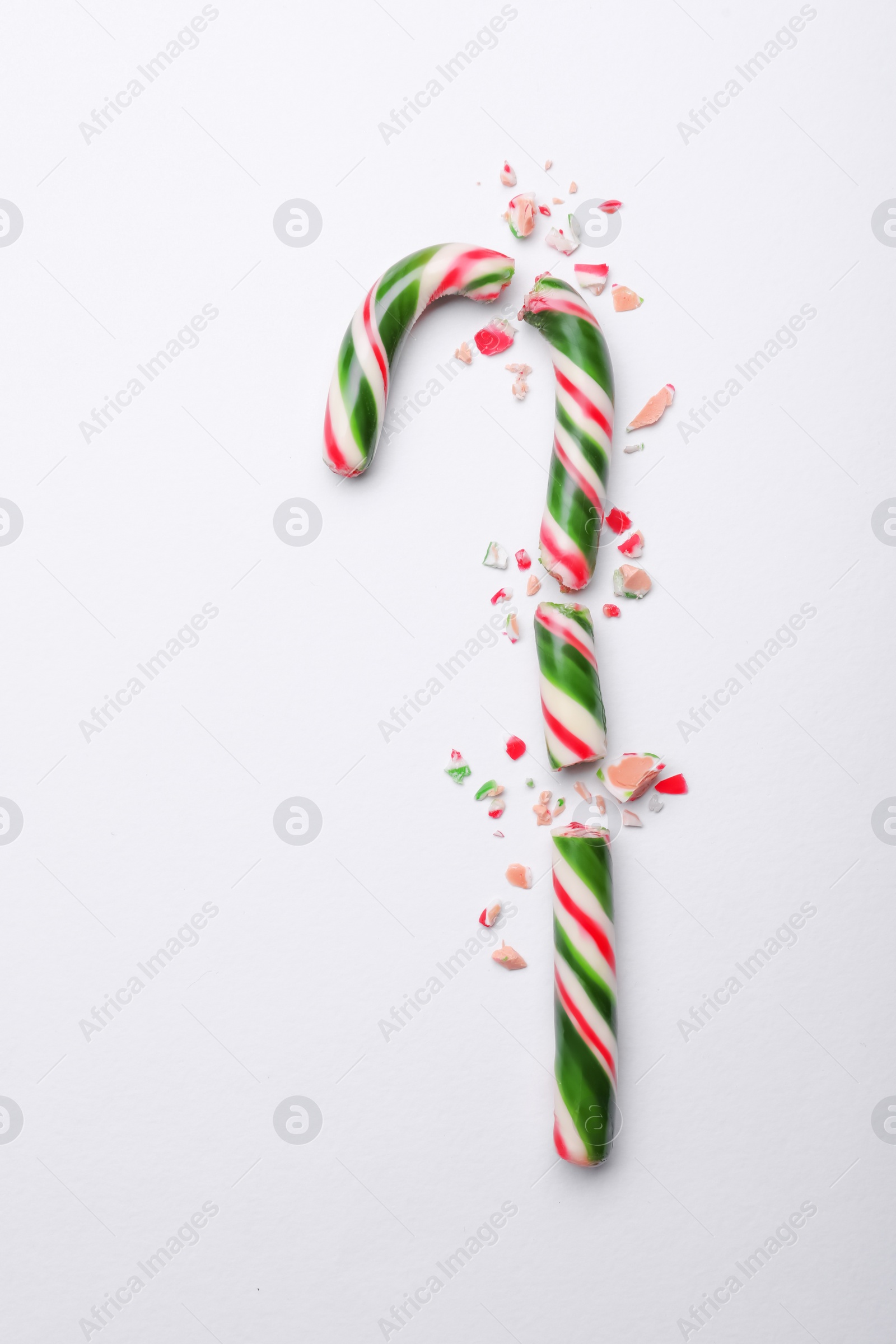 Photo of Broken sweet Christmas candy cane on white background, top view