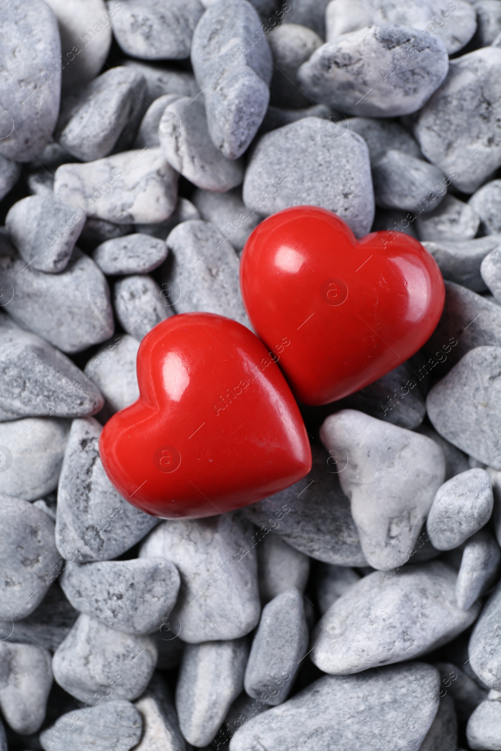 Photo of Red decorative hearts on grey stones, top view