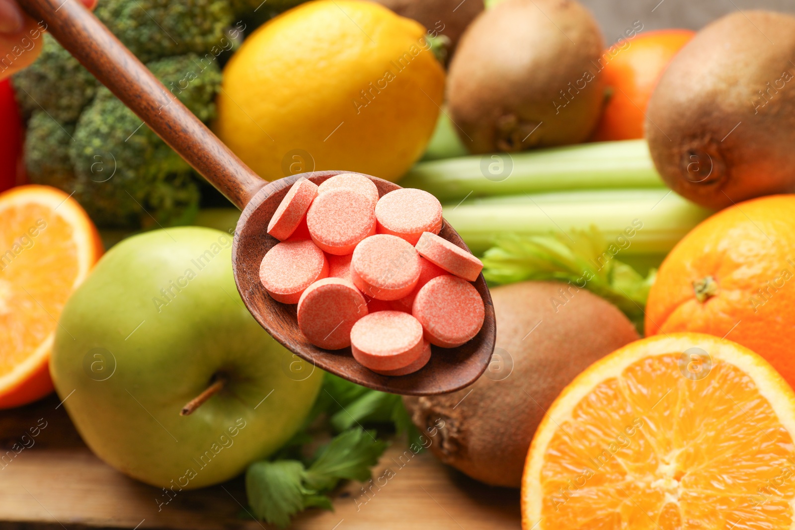 Photo of Dietary supplements. Spoon with pills over food products at table, closeup