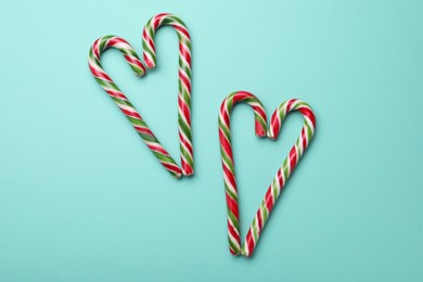 Photo of Hearts made of sweet Christmas candy canes on turquoise background, flat lay