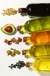 Photo of Vegetable fats. Different cooking oils in glass bottles and ingredients on white background, flat lay