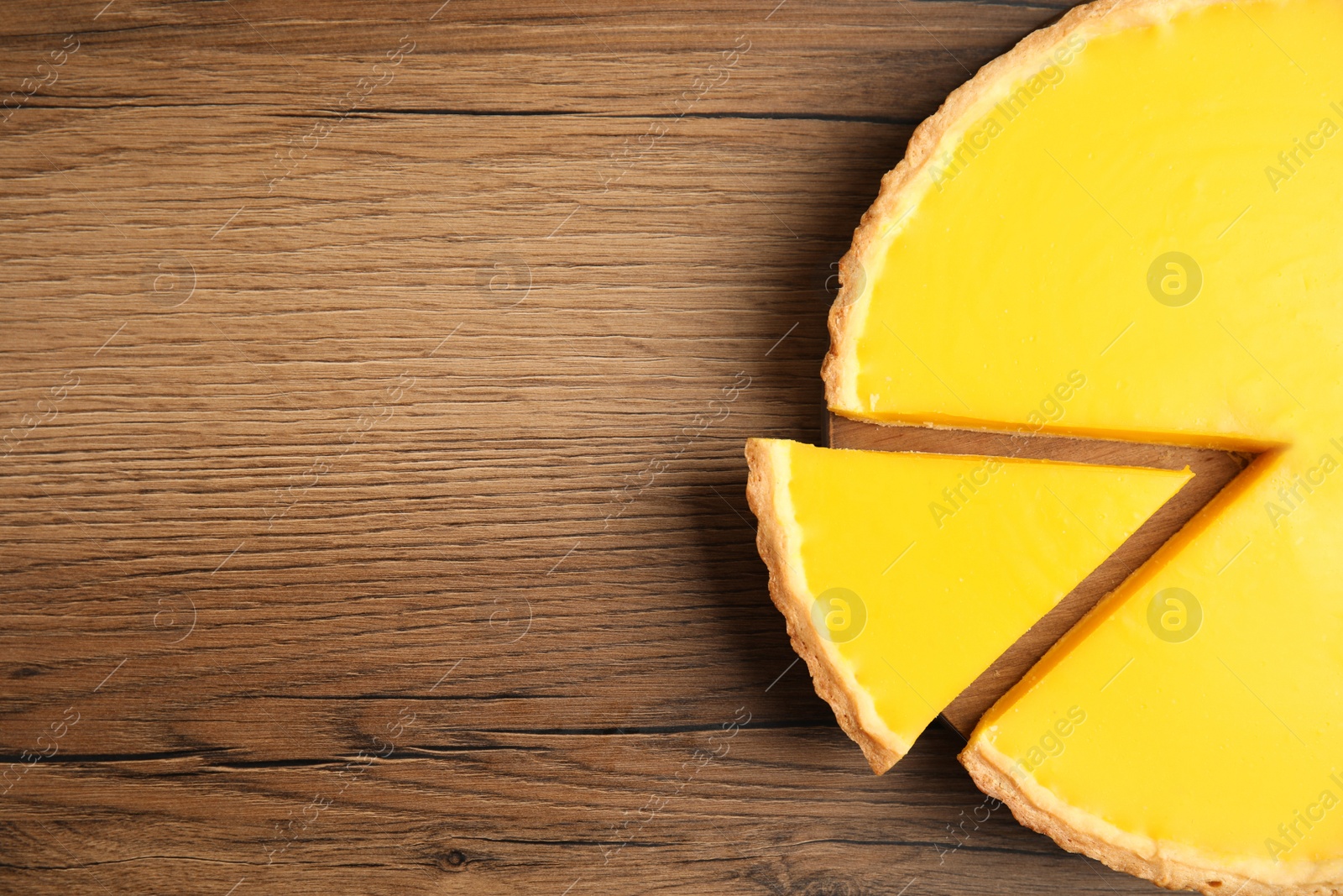 Photo of Delicious homemade lemon pie on wooden table, top view. Space for text