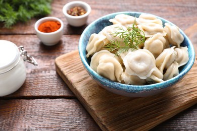 Photo of Delicious dumplings with dill on wooden table, closeup