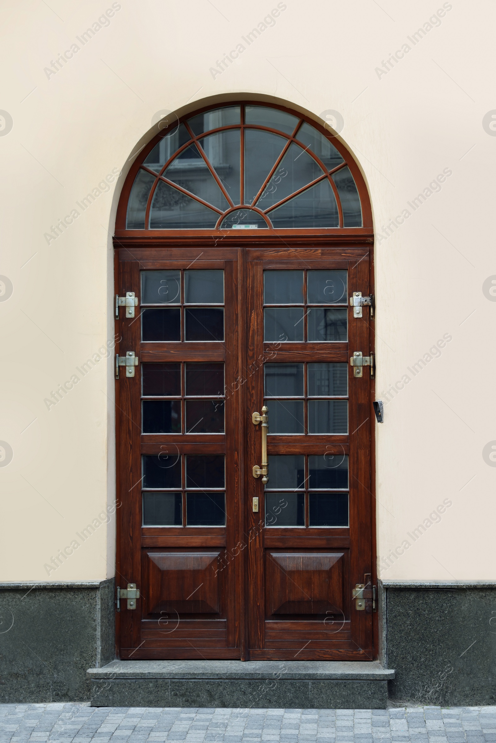 Photo of Entrance of house with beautiful arched wooden door and transom window