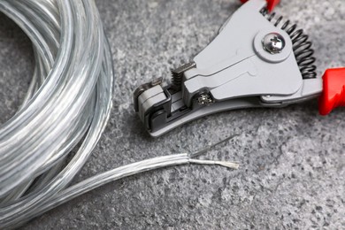 Photo of Cutters and cable with stripped wire on light gray textured table, closeup